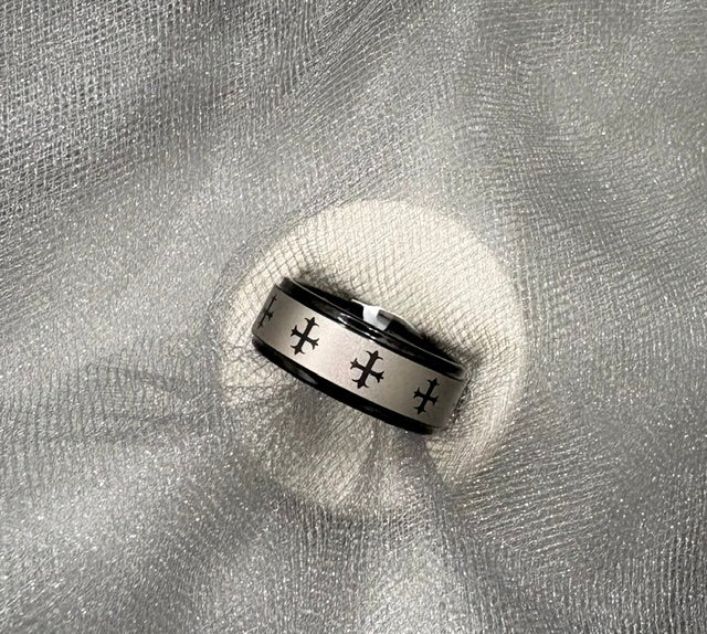 Silver ring with engraved designs on a textured gray surface