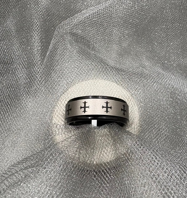 Silver ring with cross designs on a textured gray fabric background