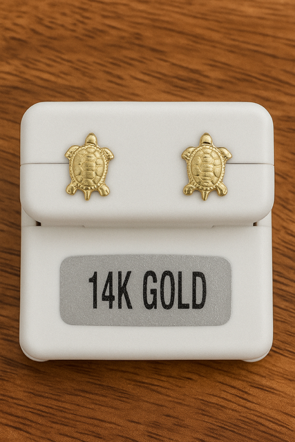 Gold turtle earrings on a white box with '14K Gold' label on a wooden surface