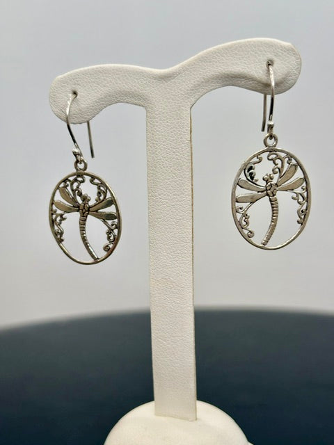 Silver dragonfly earrings on a white T-shaped stand against a gray background