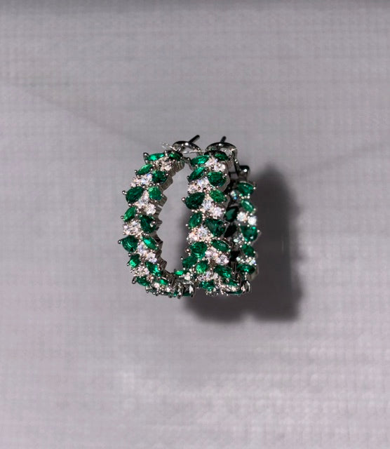 Jewelry piece with green and clear stones on a gray background