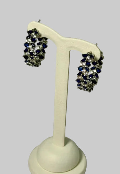 Pair of earrings on a white stand with a light gray background
