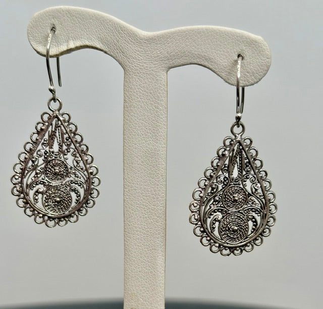 Pair of silver teardrop earrings on a display stand against a gray background